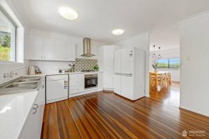 a kitchen with white appliances and a wooden floor at RELAX @48 CLOSE TO BEACH sleeps 7 in Yeppoon