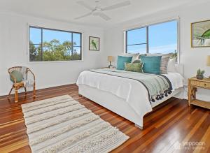 a white bedroom with a bed and two windows at RELAX @48 CLOSE TO BEACH sleeps 7 in Yeppoon