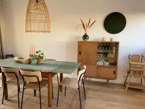 a dining room table with chairs and a clock on the wall at Le dodo mauricien in Wimereux