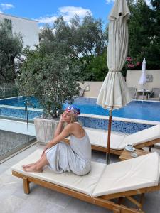 a woman sitting on a bed next to a pool at B&B Amfora in Petrovac na Moru
