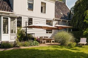 a patio with a table and umbrella in front of a house at Inn on the Lake in Broek in Waterland