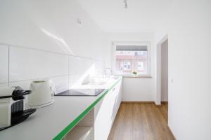 een witte keuken met een wastafel en een raam bij Glück Auf Appartements Rüttenscheiderstraße Essen in Essen