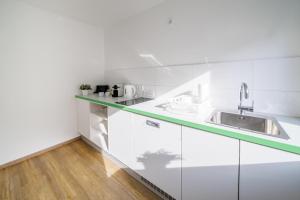 eine Küche mit weißen Schränken und einem Waschbecken in der Unterkunft Glück Auf Appartements Rüttenscheiderstraße Essen in Essen
