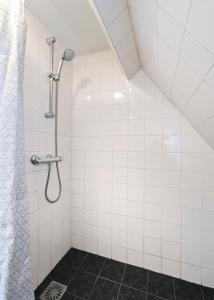 a shower in a white tiled bathroom at Idyllisch en knus huisje met prachtige veranda. in Oterleek