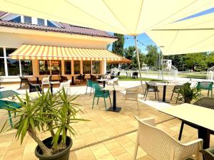 an outdoor patio with tables and chairs and umbrellas at Villa Bea Panzió in Zamárdi