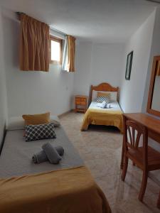 1 dormitorio con 2 camas, mesa y escritorio en Playa del Ingles Cosy Apartment, en Maspalomas