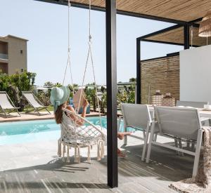a woman sitting in a chair by a swimming pool at Antigoni Seaside Resort in Ormos Panagias