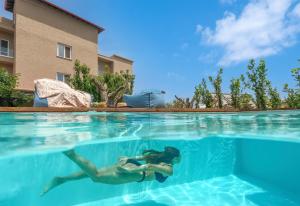 a woman swimming in the water in a swimming pool at Antigoni Seaside Resort in Ormos Panagias