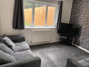 a living room with a couch and a flat screen tv at lovely4 bedroom house close to Loughborough uni/M1 in Loughborough