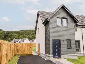 a house with a black door and a wooden fence at 6 Bynack More in Aviemore