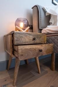 a wooden bedside table with a candle on top of it at The Arran, St Andrews in St. Andrews