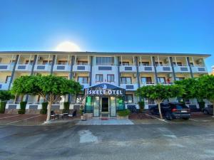 a large white building with a car parked in a parking lot at İskele Otel in Tasucu