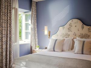 a bedroom with a bed with blue walls and a window at Hotel Supetar in Cavtat