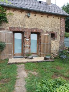 ein Backsteinhaus mit zwei Türen und einer Terrasse in der Unterkunft Maisonnette en campagne "Le Rocher" in Vibraye