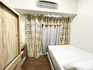 a small bedroom with a bed and a curtain at Netflix all day in Lovely 1BR with Balcony Condo AIR Residences in Manila