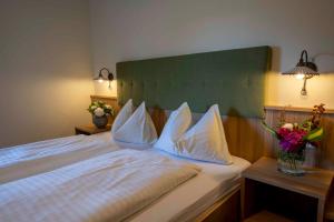 1 dormitorio con 1 cama con almohadas blancas y flores en Landhotel Pacher en Obervellach