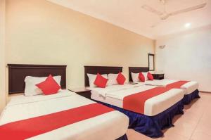 two beds in a hotel room with red and white pillows at Hotel Home 88 in Teluk Intan