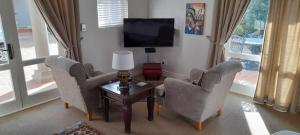 a living room with two chairs and a tv at Erinvale Garden cottage in Somerset West