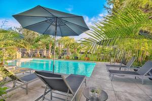 a patio with chairs and an umbrella next to a pool at Villa Tropicana Berlin Potsdam in Teltow