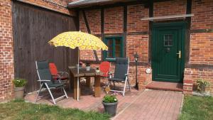 eine Terrasse mit einem Tisch, Stühlen und einem Sonnenschirm in der Unterkunft Ferienwohnung am Storchennest in Kambs