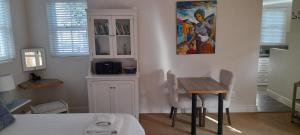 a bedroom with a table and a painting on the wall at Erinvale Garden cottage in Somerset West