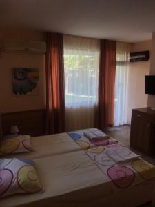 a bedroom with a bed with pillows and a window at Family Hotel Astra in Chernomorets