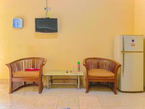 a room with two chairs and a table and a refrigerator at Wisma Apada Syariah Sengkang Mitra RedDoorz in Singkang