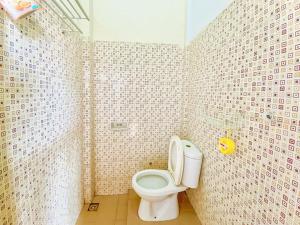 a bathroom with a toilet and a tiled wall at Wisma Apada Syariah Sengkang Mitra RedDoorz in Singkang