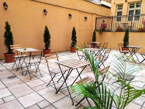 un patio con mesas, sillas y macetas en Quentin Prague Hotel, en Praga