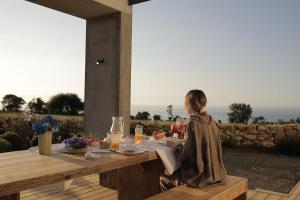 a woman sitting at a wooden table with food on it at El Faro Unkempt - Tazones in Villar