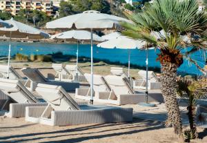 un gruppo di sedie e ombrelloni in spiaggia di Melbeach Hotel & Spa - Adults Only a Canyamel