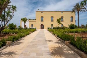 a large yellow building with palm trees in front of it at Tenuta Rocci Cerasoli in Parabita