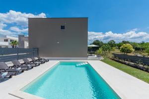 - une piscine avec des chaises et une maison dans l'établissement Villa Atena, à Poreč