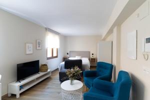 sala de estar con 1 cama y 2 sillas azules en Housingleón Azabachería 22, en León