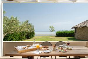 a table with food and drinks and a view of the ocean at Antigoni Seaside Resort in Ormos Panagias