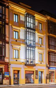 ein großes gelbes Gebäude mit einem großen Fenster in der Unterkunft Apartamentos La Xiuca Playa in Gijón