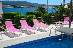 une rangée de chaises roses assises à côté d'une piscine dans l'établissement Aparthotel Vibra Sanan - Adults only, à Sant Antoni de Portmany