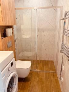 y baño con ducha, aseo y lavadora. en Rimos apartamentai Juodkranteje, en Juodkrantė