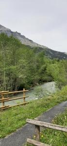 un banco en un camino junto a un río en Un havre de paix aux pieds des chemins de montagne, en Les Contamines-Montjoie