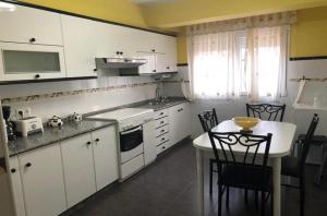 a kitchen with white cabinets and a table with chairs at Vistalmar Laxe in Laxe