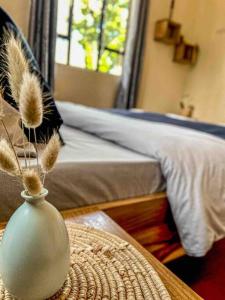 a bedroom with a bed and a vase on a table at gemütlicher Bungalow x Garten & Terrasse x NETFLiX in Moshi