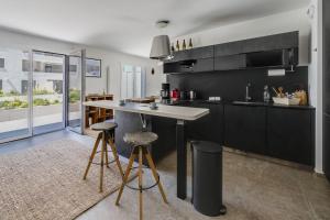 una cocina con armarios negros y una barra con taburetes en Envie de Lac - Nice T3 for 6 people near Beach en Annecy
