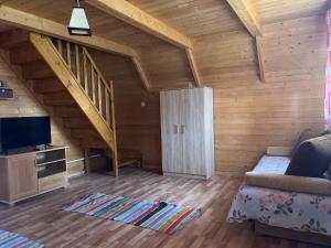 a living room with a staircase and a couch and a tv at Całoroczne Domki Aga in Hoczew