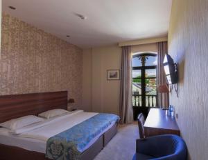 a bedroom with a bed and a desk and a window at Old Meidan Tbilisi By Urban Hotels in Tbilisi City