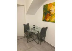 einen Glastisch mit zwei Stühlen und ein Gemälde an der Wand in der Unterkunft Brilliant Souterrain Apt. - Prater Amuesement Park in Wien