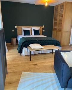 a bedroom with a large bed with a green blanket at Lodge La Courrège in Larché