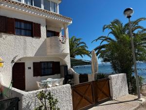 a house on the beach with a gate and a surfboard at Chalet en el mar in La Manga del Mar Menor
