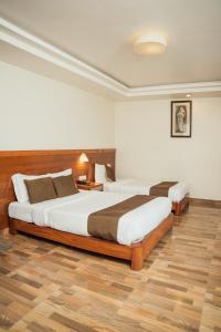 two beds in a hotel room with wooden floors at Mount View Pokhara in Pokhara