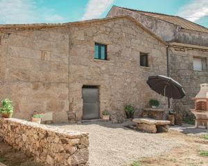 a stone building with an umbrella in front of it at Casa da Eira de Santo Amaro in Ponte da Barca