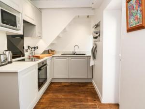 a kitchen with white cabinets and a sink at Chough Cottage in Penzance